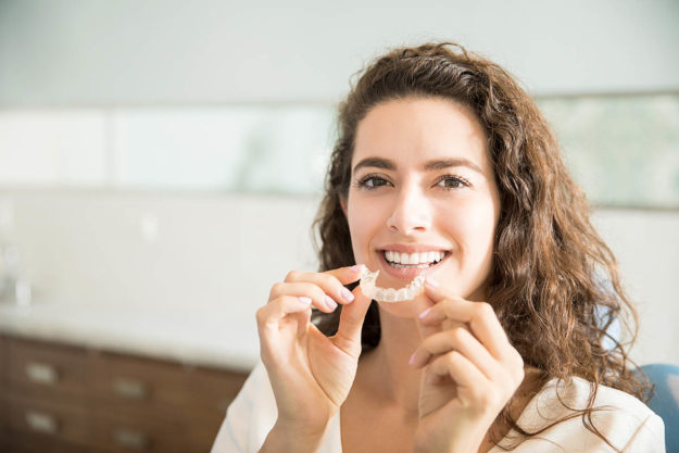woman putting in retainer to prevent teeth shifting