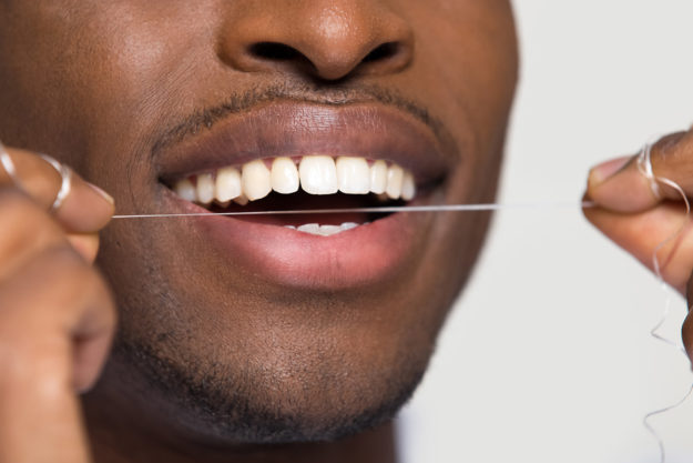 a man flossing after learning the benefits of flossing daily