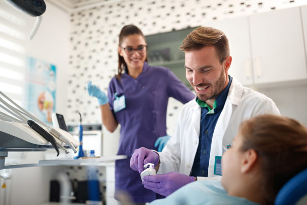 a dentists explaining to a patient how they can fix a pediatric dental emergency