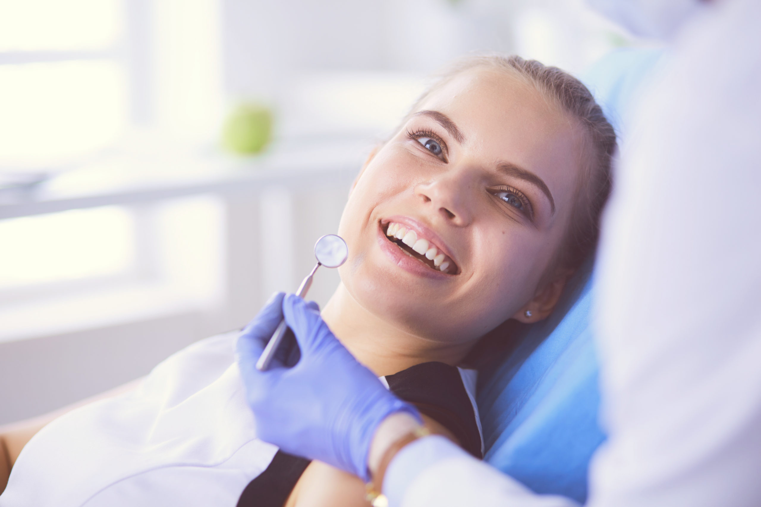 Young Female patient with pretty smile examining dental inspection at dentist office. woman asking dentist about oral surgery vs emergency dentistry