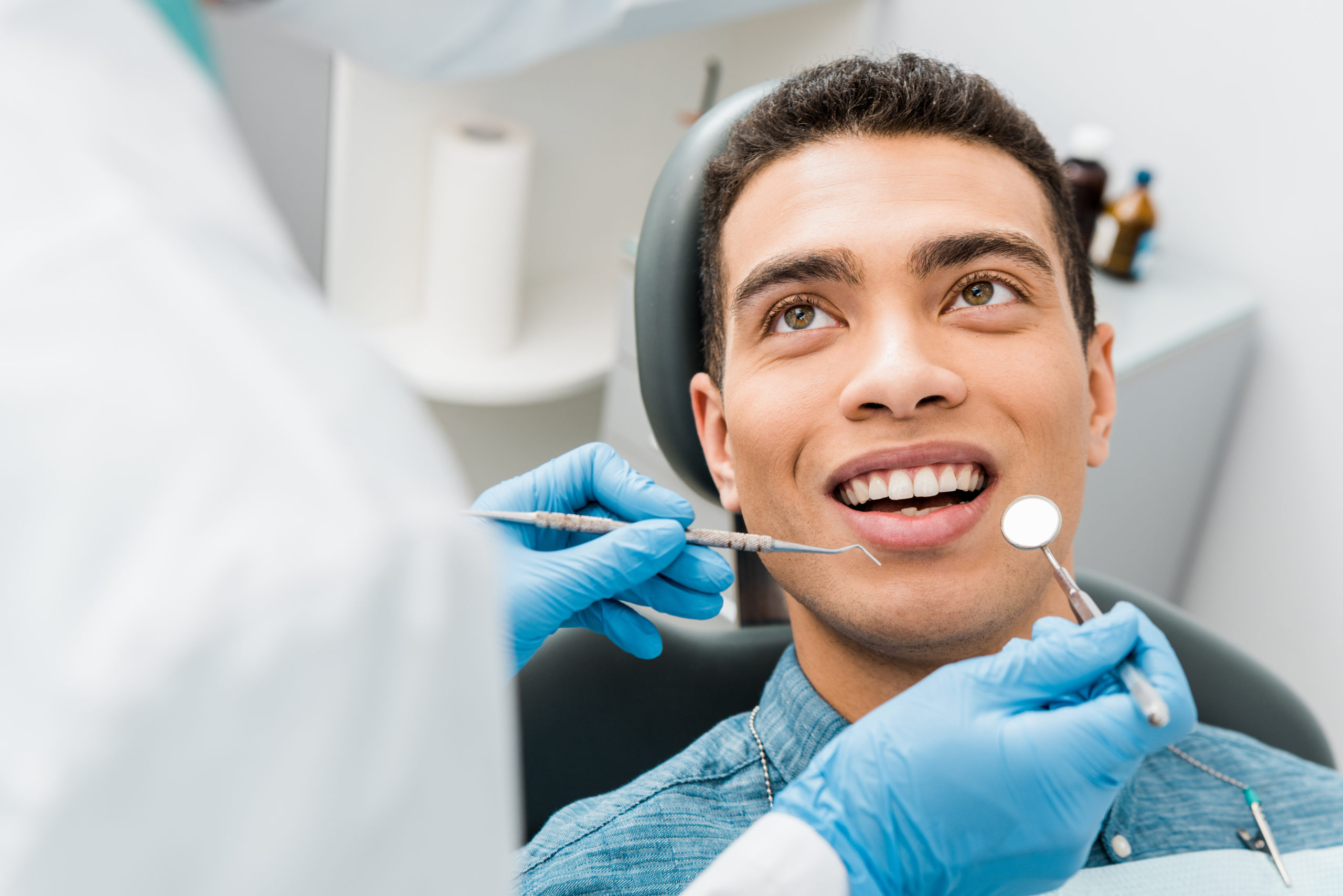 cheerful african american man with during examination in dental clinic man getting dental sealants
